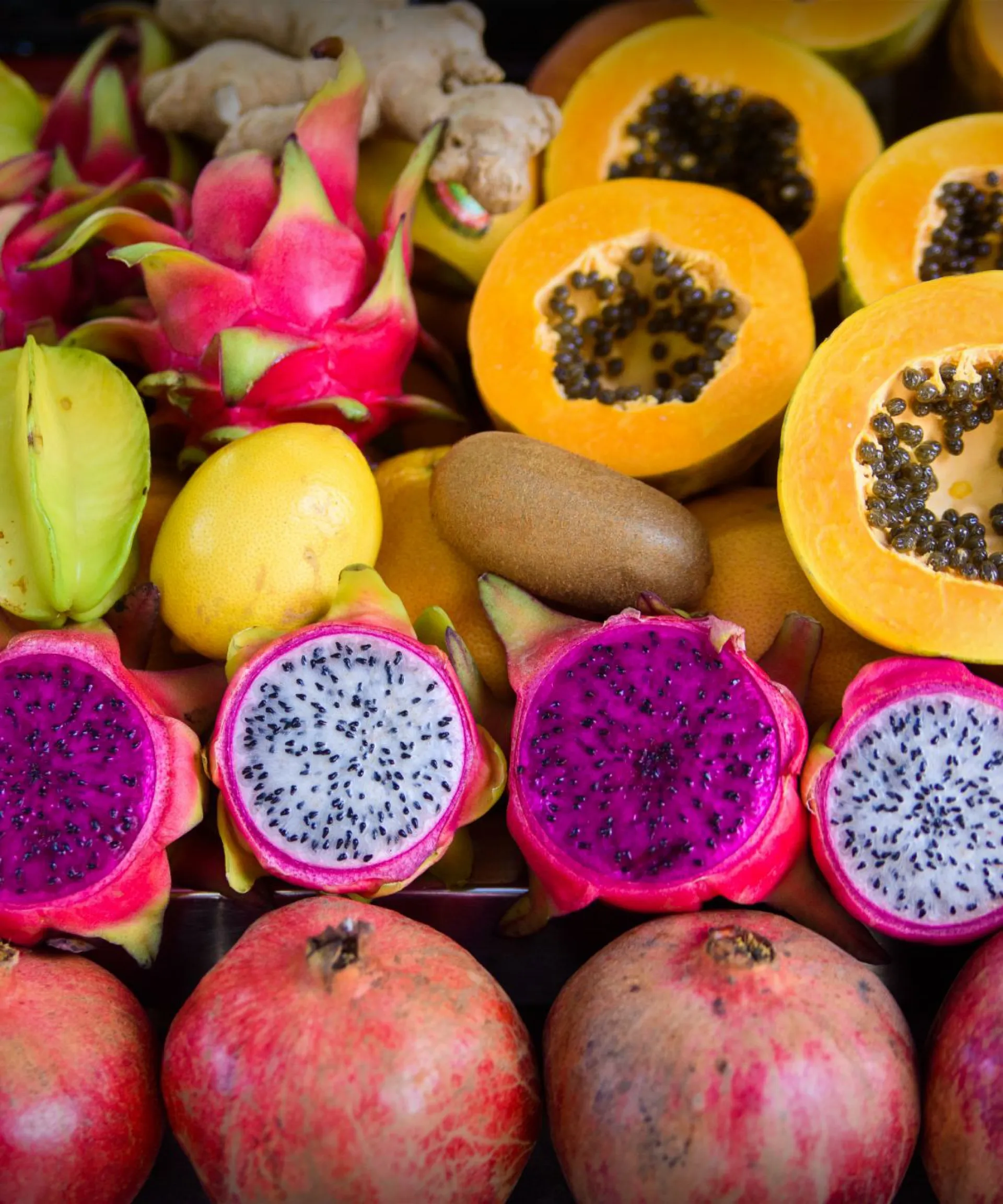 Assorted tropical fruits including dragon fruit, papaya, starfruit, and pomegranate.